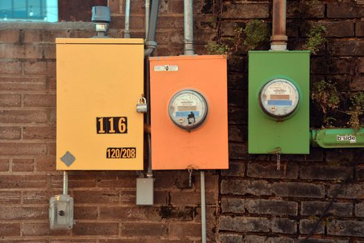 Three vibrant utility meters on a brick wall showcasing urban industrial design in Texarkana, Texas.