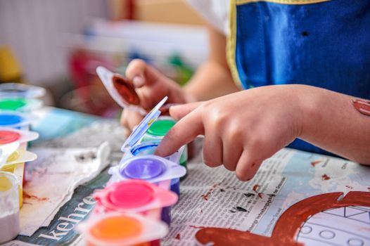 A close-up of a child finger painting with vibrant colors, showcasing creativity and focus.